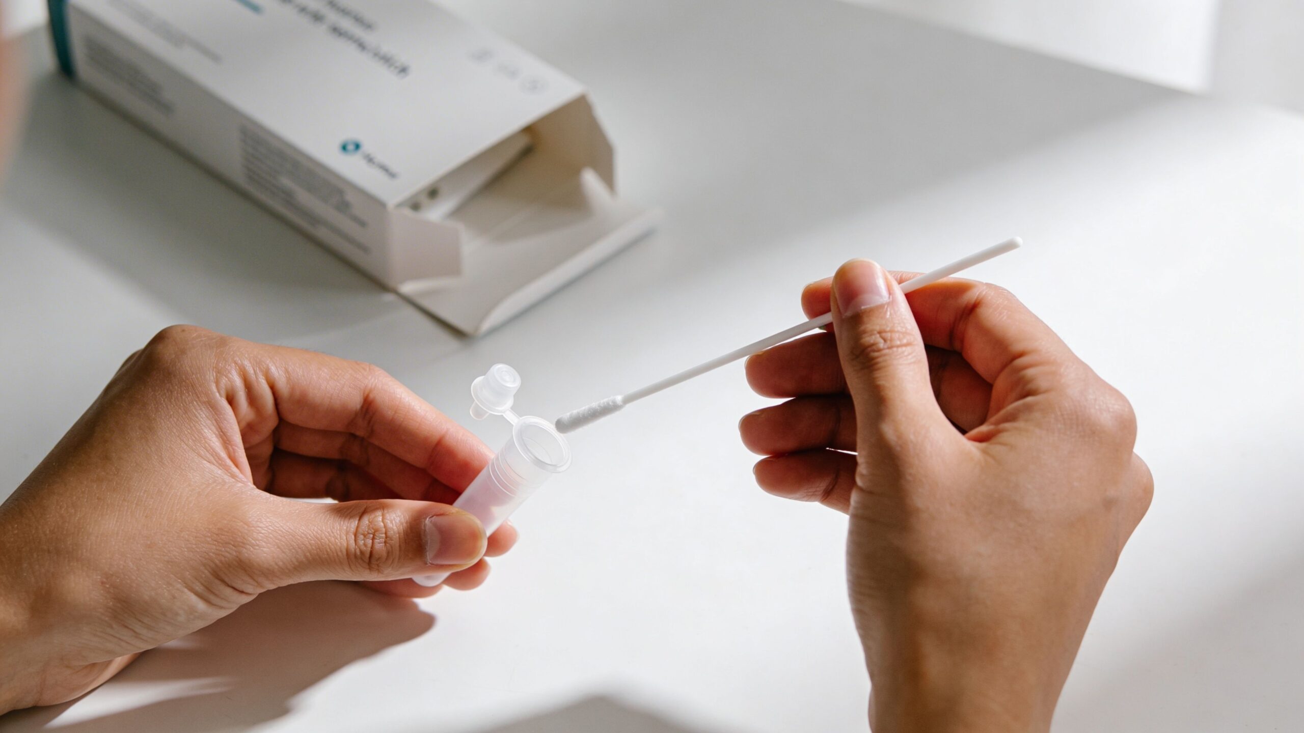 A person preparing to use an STI testing kit with a sterile swab and collection tube.
