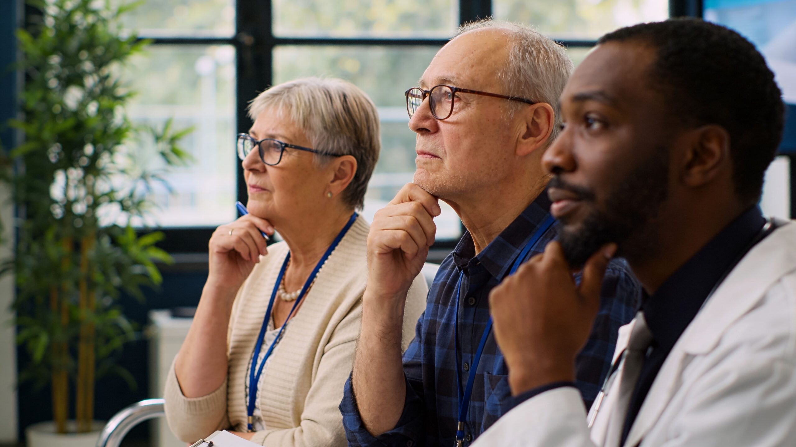 A diverse group of people attending a professional medical seminar and listening attentively in a bright office.